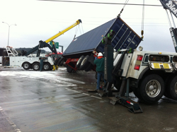 turned-over trailer being up-righted by tow trucks