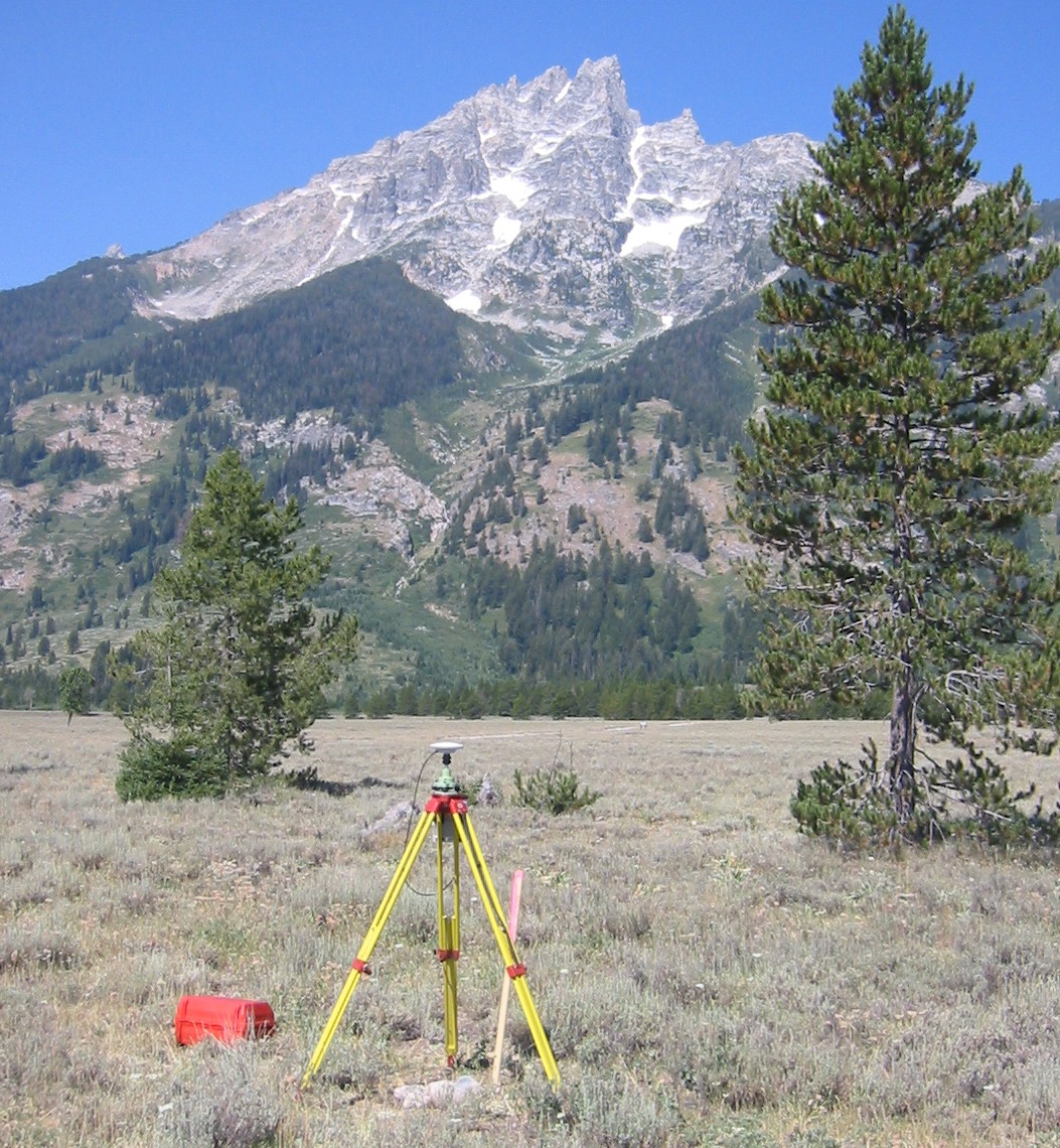 photo of survey equipment in a field with a mountain in the near distance